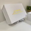Caja personalizada con dos diseños, rígida y magnética, con la inscripción Alessandra en dorado y una cinta, junto a una pequeña planta verde.