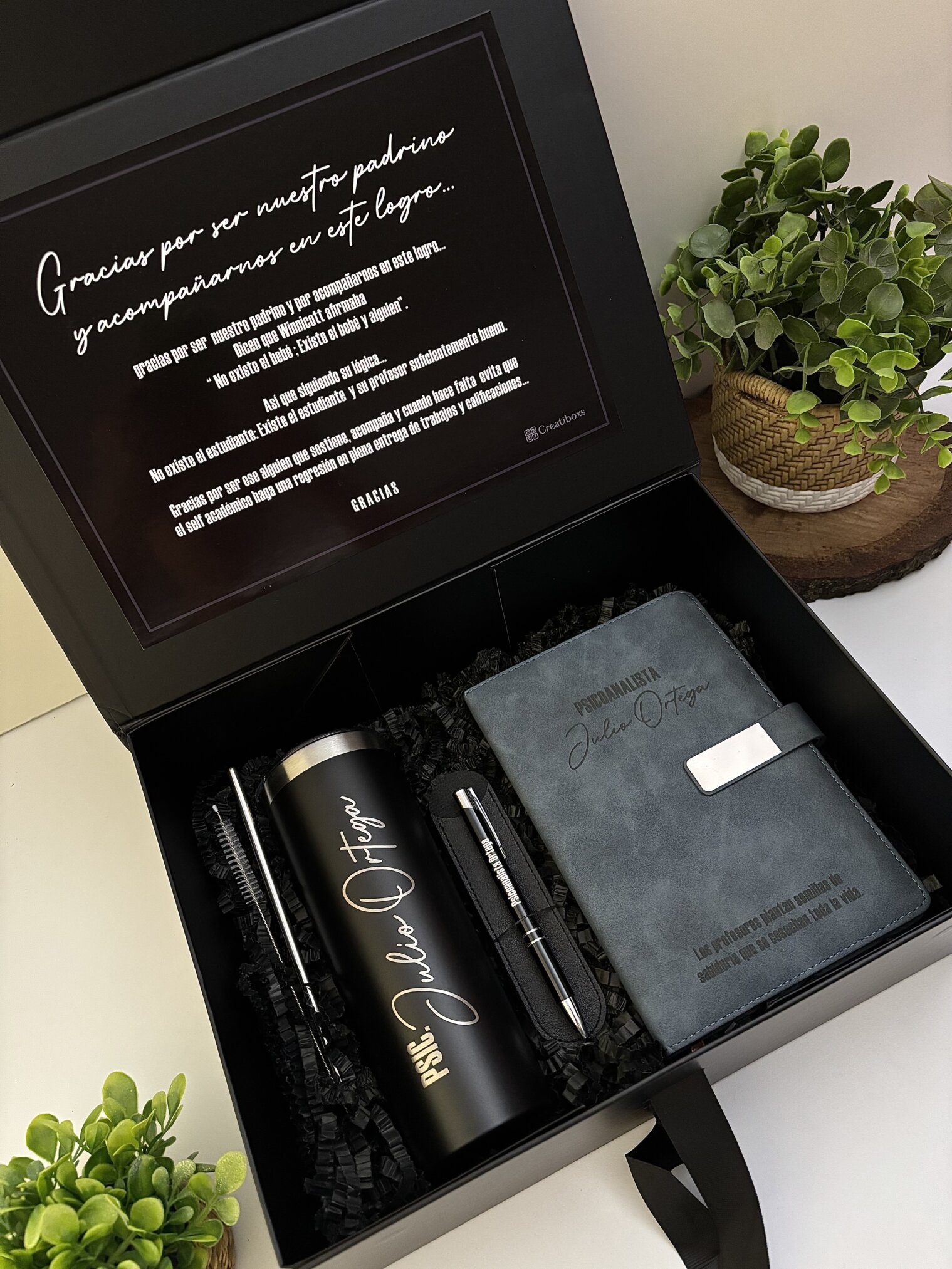 Kit regalo personalizado en caja con termo delgado 590ml, libreta broche metálico y bolígrafo, acompañado de nota en español y rodeado de pequeñas plantas-el detalle perfecto para cualquier ocasión.