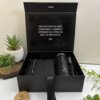 Caja regalo con Kit regalo personalizado en caja: termo delgado 590ml, libreta cierre magnético vertical y bolígrafo, más mensaje de agradecimiento en español, todo decorado entre pequeñas plantas.