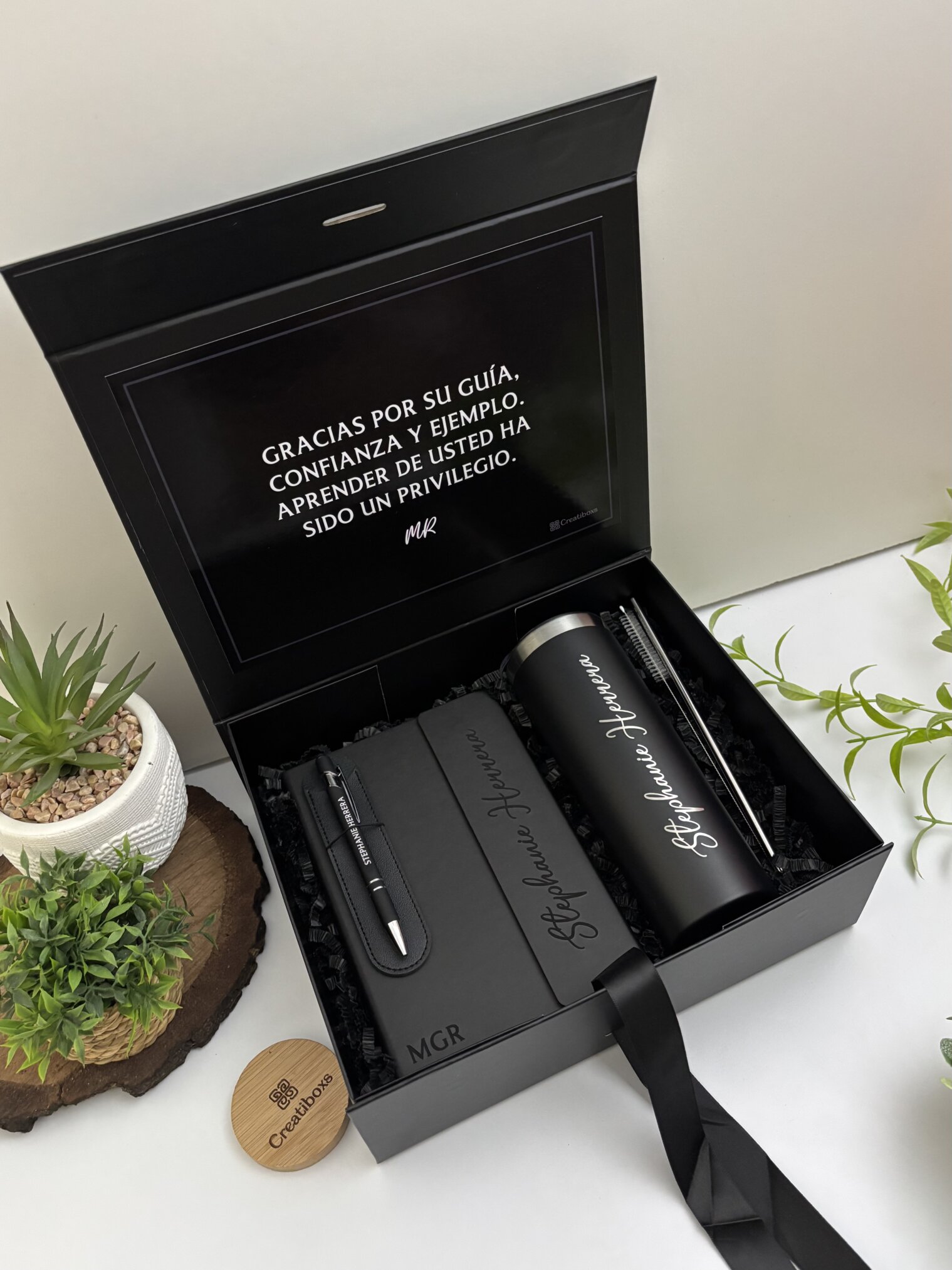 Kit regalo personalizado en caja negra con termo delgado 590ml, libreta cierre magnético vertical y bolígrafo. Incluye mensaje de agradecimiento en español. Perfecto para cualquier ocasión especial.