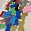 Placas de identificación para mascota personalizadas en forma de hueso de aluminio, algunas con llavero, están esparcidas junto a un calibrador blanco sobre una superficie beige.
