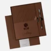 Agenda semanal clásica personalizada de 2027 en color marrón, con bolígrafo, presentada en caja y con el logotipo BC25 y la firma en la portada.