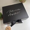 Caja de regalo negra con un lazo que contiene un kit de regalo personalizado en caja con taza térmica de 360 ml (12 oz), un cuaderno con cierre metálico y un bolígrafo con la inscripción ¡Felicidades, arquitecto!.